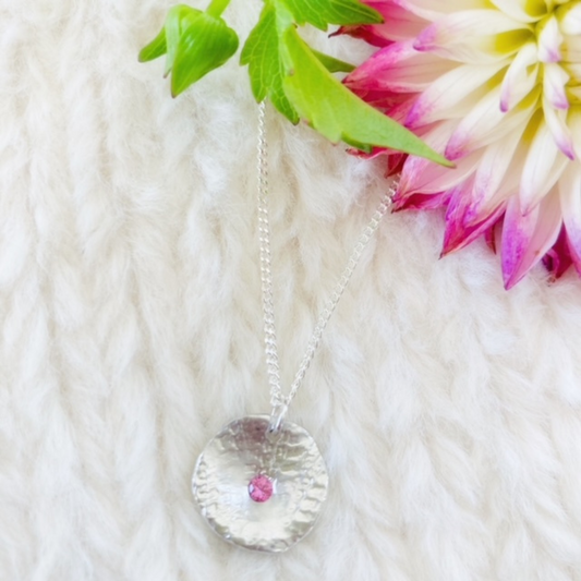 The mina necklace includes a bright pink sapphire nestled in sterling silver with a unique texture.  The sapphire is 3mm, pendant measures approx. 1.5 cm in length and comes on an adjustable 16-18” shiny sterling silver chain.