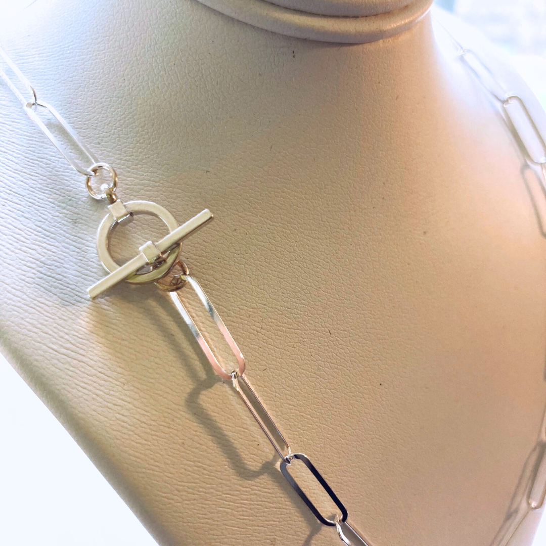 This version of a paperclip chain is a sterling silver oval cable chain with a sleek toggle clasp also sterling silver.