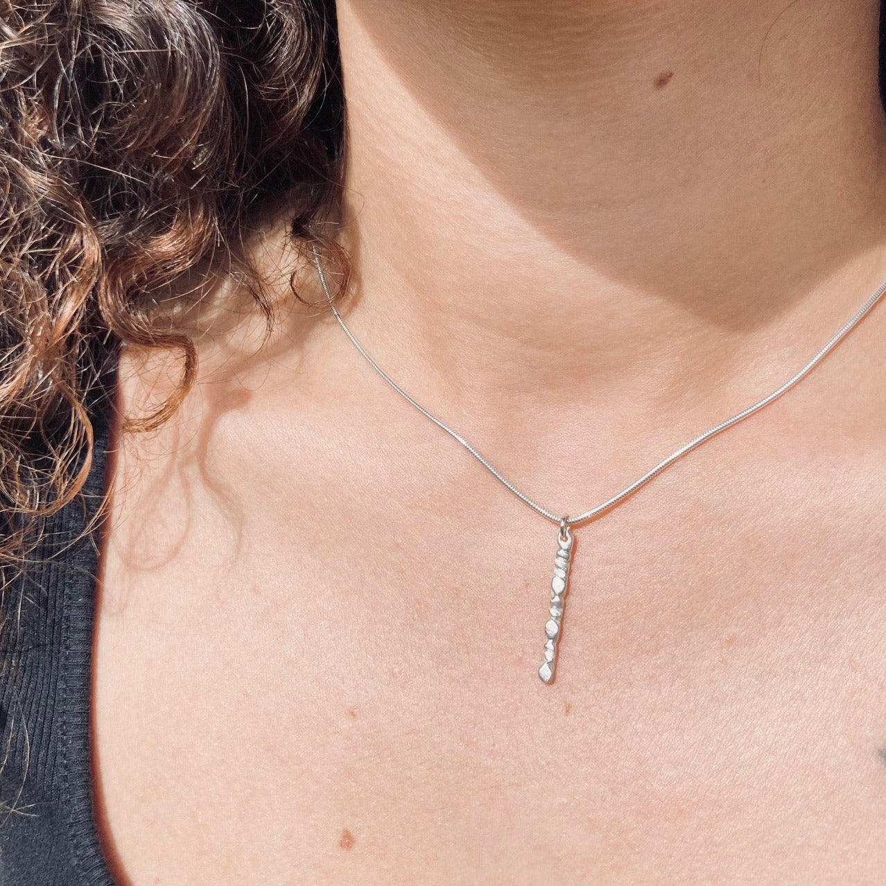 A beautiful mixed metals piece. The 1” vertical bar is a handcarved fortenna design providing texture and visual detail. The bar is 14k gold plated over brass and the chain is a shimmery sterling silver adjustable 16-18” chain. Model shown wearing all sterling silver version.