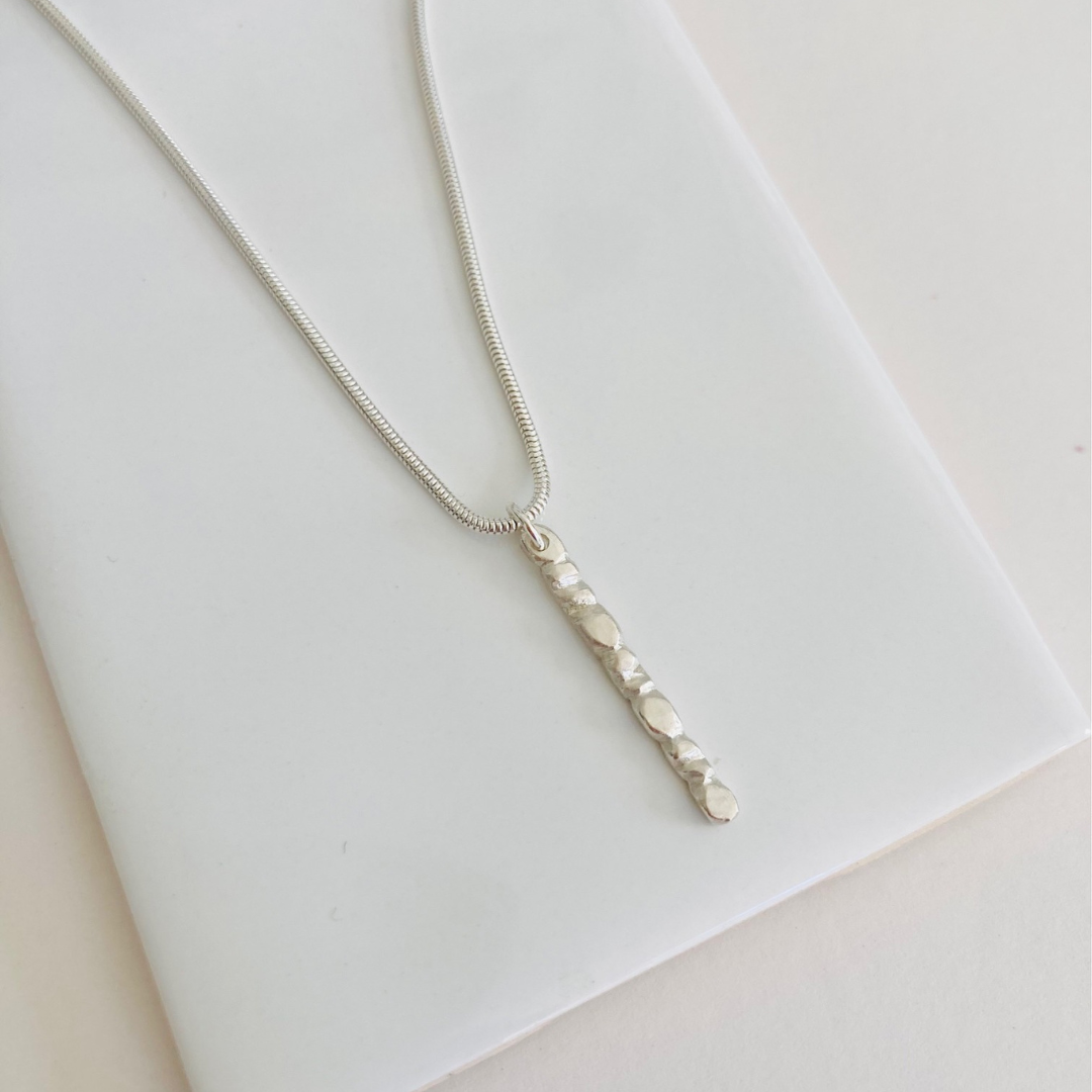 The sterling silver 1" bar is a handcarved fortenna™ design providing texture and visual detail. Tumbled for a lightly polished look. Comes on adjustable 16-18" sterling silver snake chain.