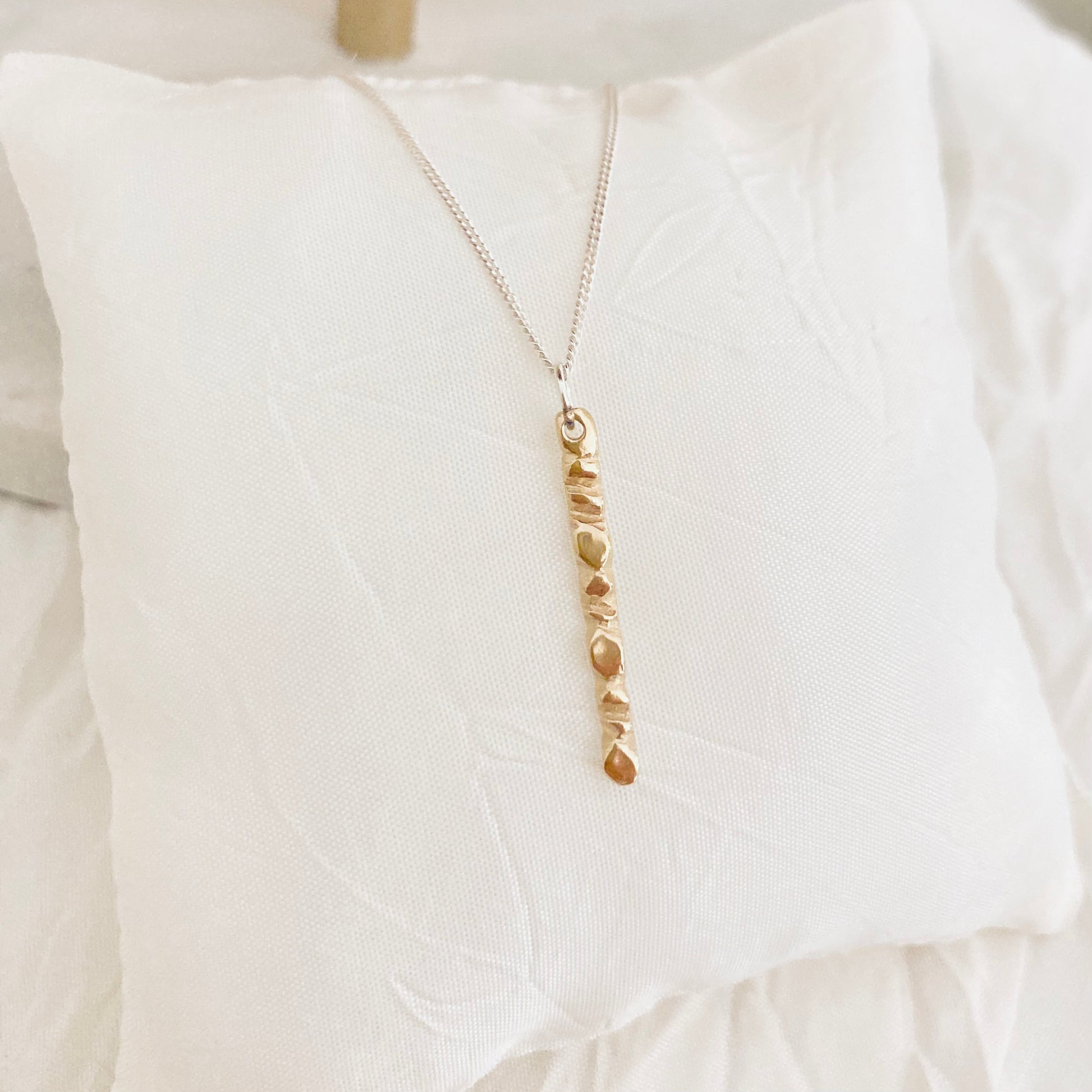 A beautiful mixed metals piece. The 1” vertical bar is a handcarved fortenna design providing texture and visual detail. The bar is 14k gold plated over brass and the chain is a shimmery sterling silver adjustable 16-18” chain.