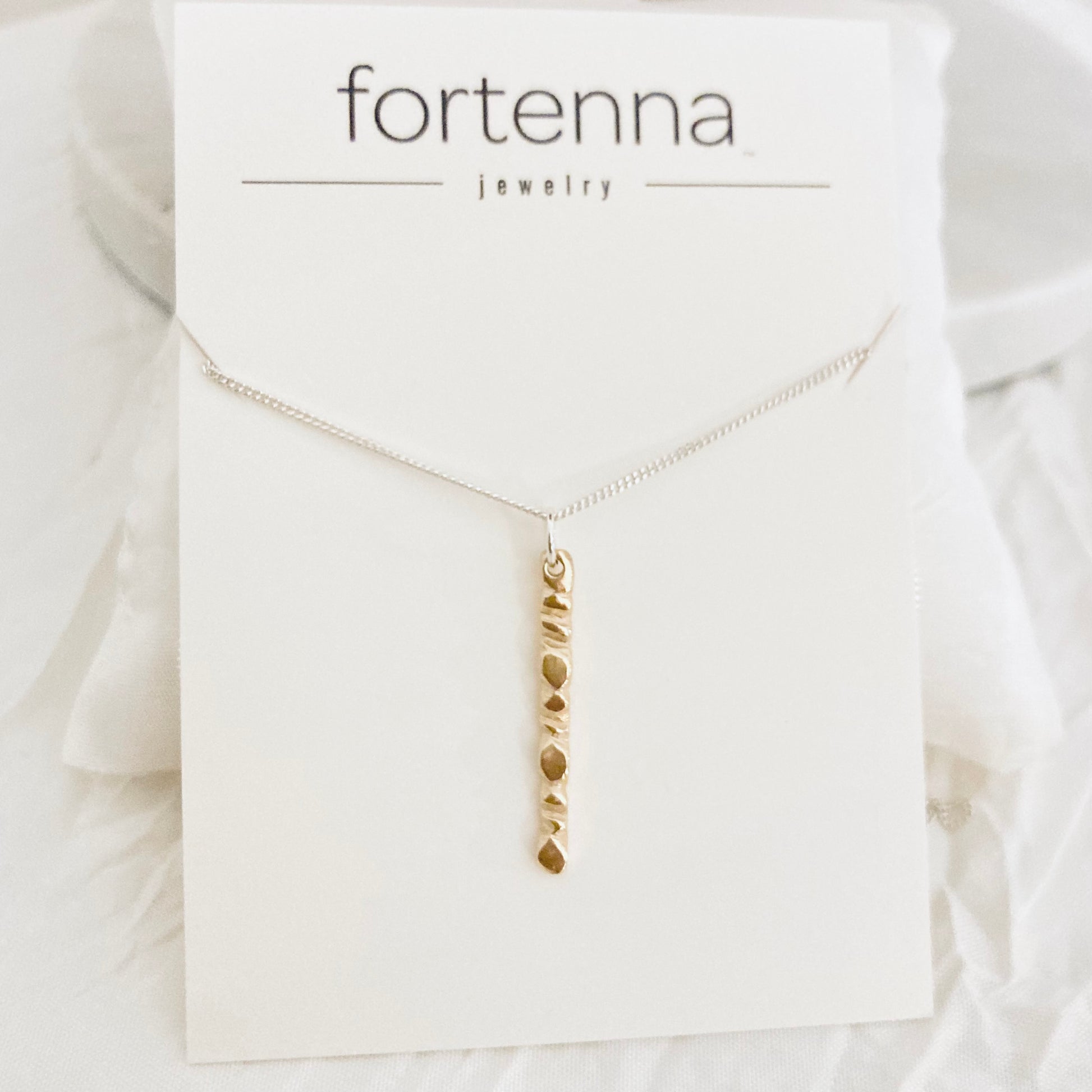 A beautiful mixed metals piece. The 1” vertical bar is a handcarved fortenna design providing texture and visual detail. The bar is 14k gold plated over brass and the chain is a shimmery sterling silver adjustable 16-18” chain.