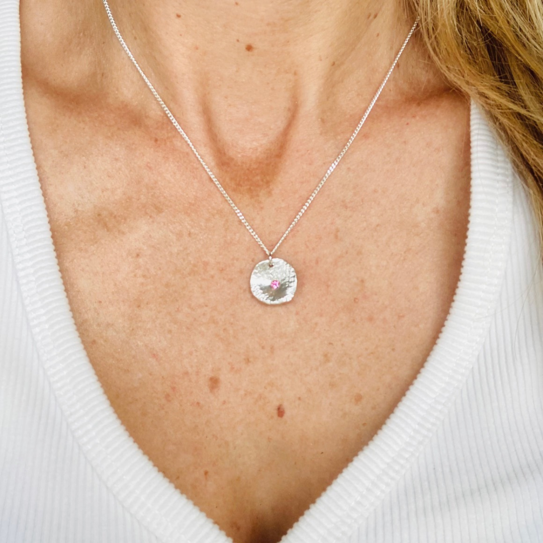 The mina necklace includes a bright pink sapphire nestled in sterling silver with a unique texture.  The sapphire is 3mm, pendant measures approx. 1.5 cm in length and comes on an adjustable 16-18” shiny sterling silver chain.