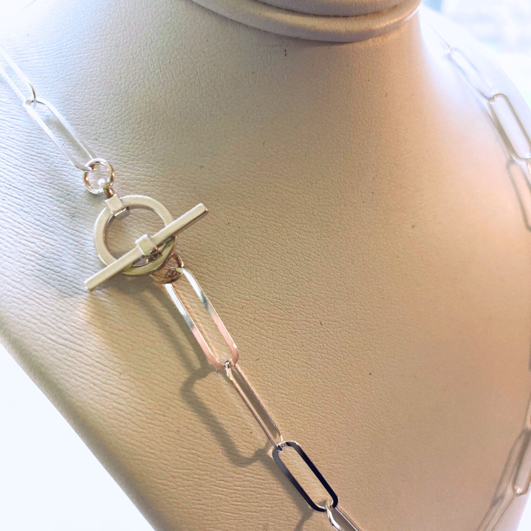 This version of a paperclip chain is a sterling silver oval cable chain with a sleek toggle clasp also sterling silver. 