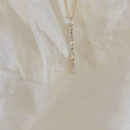 A beautiful mixed metals piece. The 1” vertical bar is a handcarved sterling silver design providing texture and visual detail. Tumbled for a lightly polished look. Comes on an 18” 14k gold-filled chain.